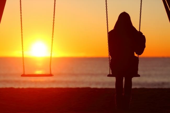 A teenage girl on a swing in the sunset