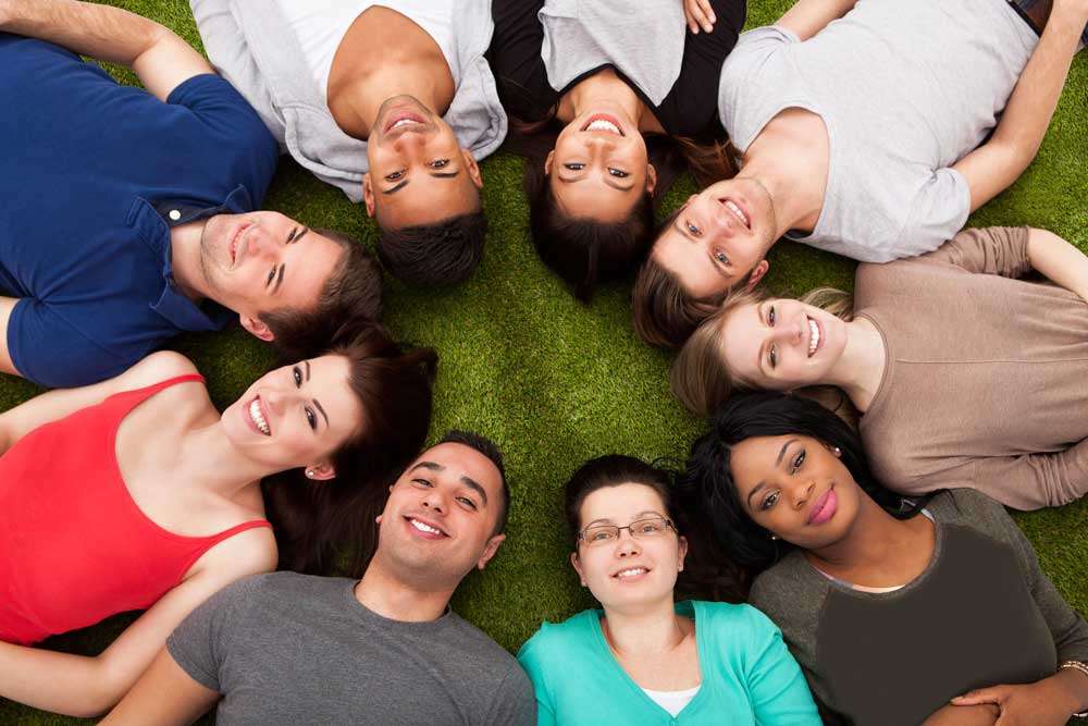 College students laying in grass in circle