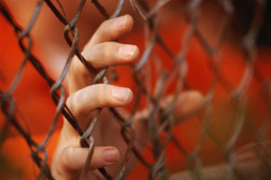 Image of hands on a jail fence