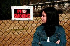 Girl standing next to No Smoking sign