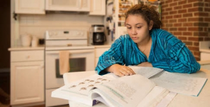 Photo of a young girl studying at her kitchen table